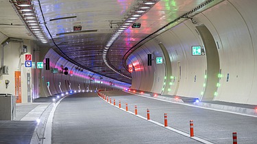 Das Bild zeigt den bunt beleuchteten Tunnel von slowenischer Seite kommend