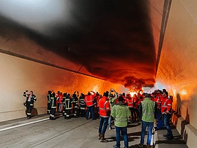Bild von einem Brand im Tunnel mit Feuerwehr und SISS Mitarbeitern