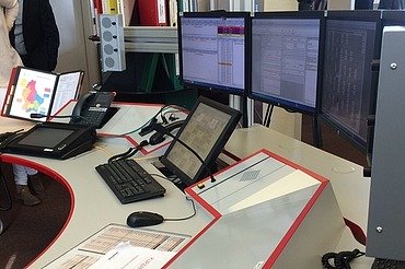 Bild eines Leitstellentisches mit Bildschirmen und Bediengeräten