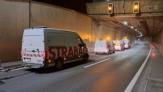 The image shows several STRABAG service vehicles in a closed tunnel
