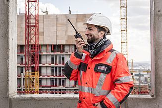 The picture shows a man on a construction site with a radio