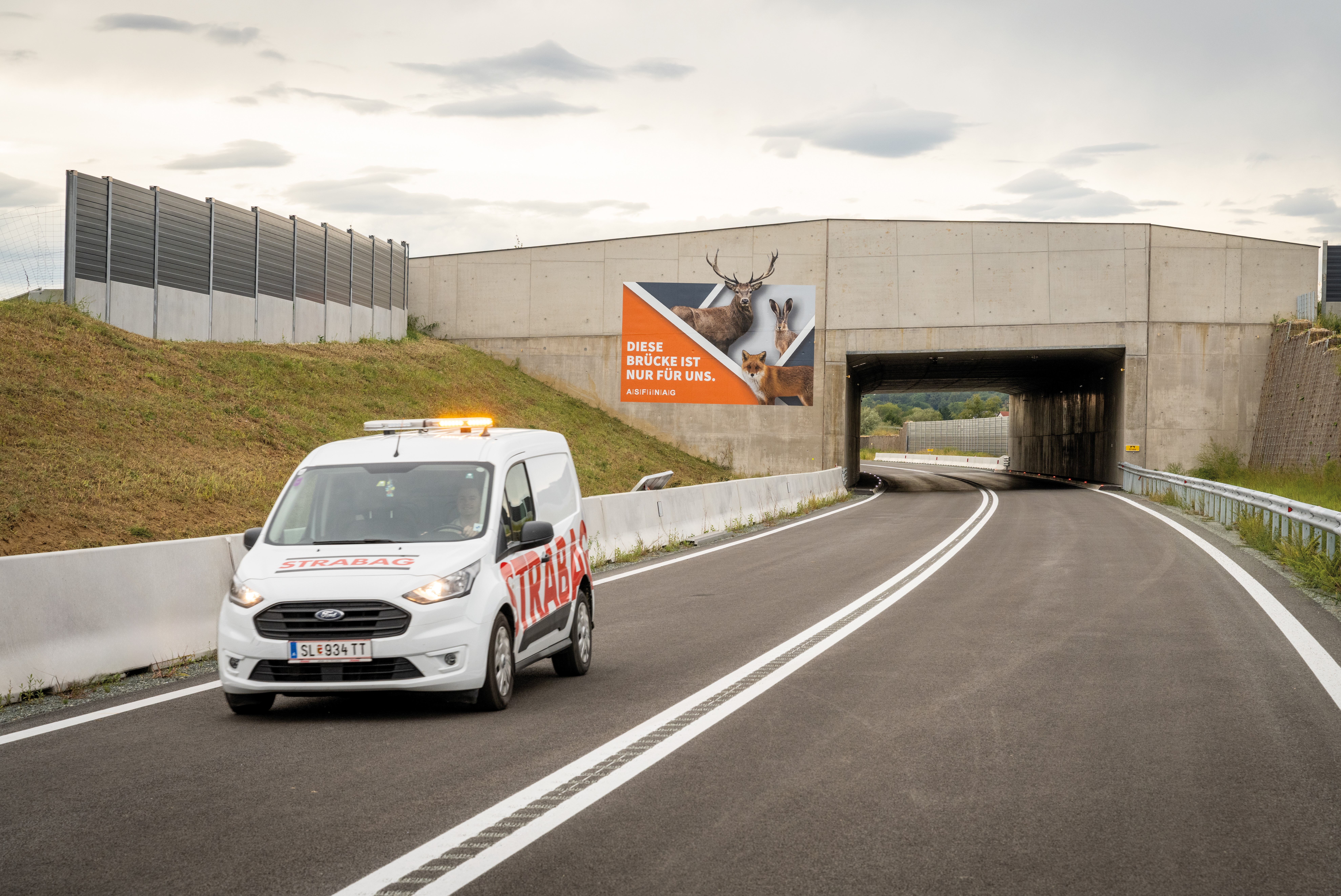 The image shows a STRABAG service vehicle on an empty road