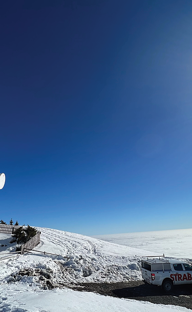 Bild von einem Mast in verschneiter hügeliger Landschaft