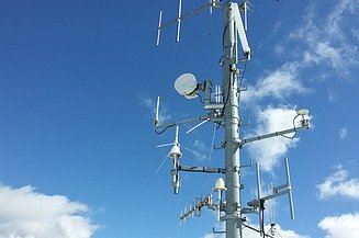 The picture shows a mast with different antennas and radio components
