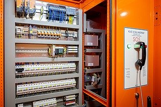 The picture shows an emergency call pillar and an open switch cabinet