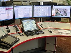 Image of a control center desk with screens and operating devices