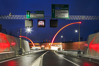Einfahrt in den Marieholmstunnel mit beleuchteter Schrankenanlage in der Dunkelheit