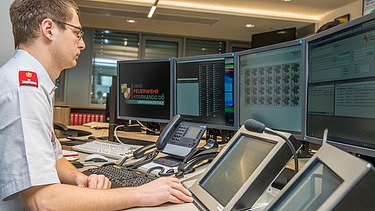 The picture shows a dispatcher, screens, and systems on a control center desk.