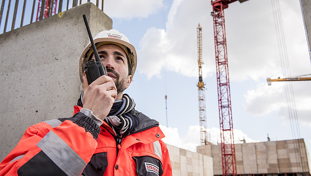 The picture shows a man with a radio on the construction site