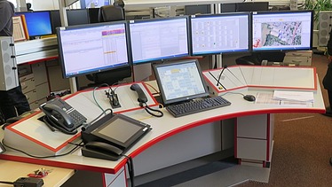Image of a control center desk with screens and operating devices