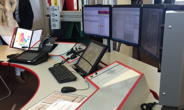 Picture of a control center desk with screens and operating devices
